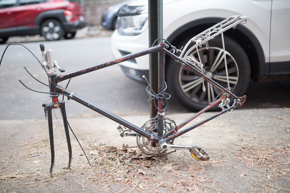 Bike stripped for parts, "locked" to pole with coaxial cable